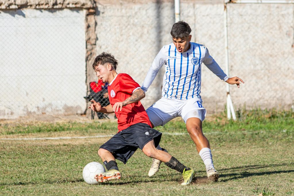 Dynamic action shot of two soccer players competing fiercely during a match on a grassy field.